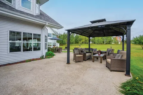 Gazebo with a table and chairs beside planted gardens