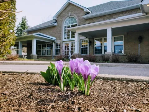 Residence entrance with stone walls and flowering garden beds.