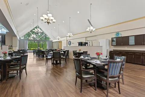 Dining room with set tables, wooden chairs and a vaulted ceiling.