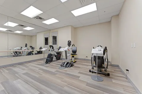 Fitness room with exercise machines and a mirrored wall.