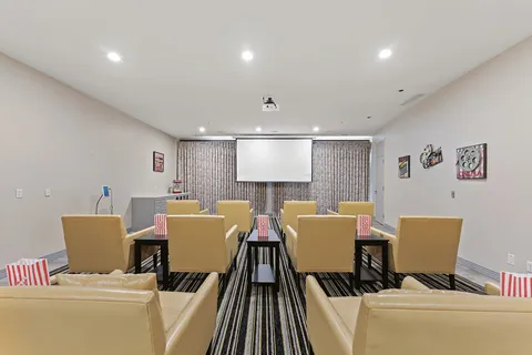 Theatre with upholstered seats and a projection screen.