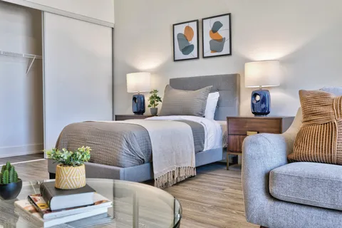 Studio bedroom with a bed, armchair, bedside cabinets and lamps.