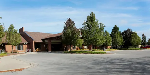Brick residence with a broad sloping roof, a covered entrance and a paved driveway