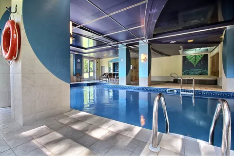 Indoor swimming pool with blue walls and a tiled surround