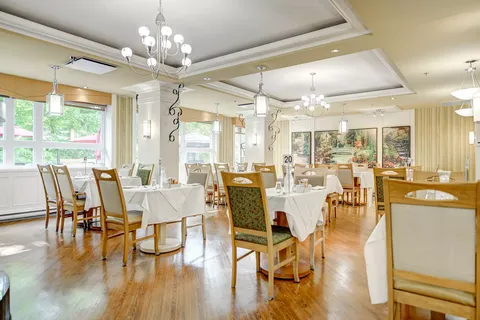 Dining room with set tables, wood-framed chairs and chandeliers