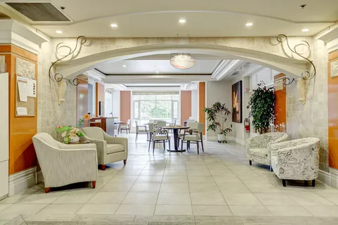 Armchairs beneath a stone archway beside tables, chairs and plants