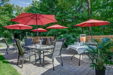 Garden patio with tables, chairs, red umbrellas and a wooden fence