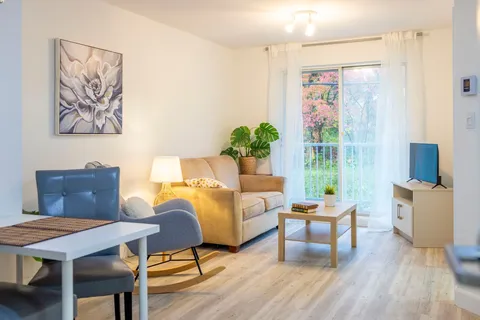 Sitting area with a sofa, an armchair, a television and a small dining table