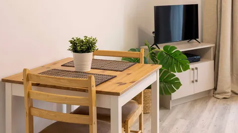 Small wooden table beside a television and potted plants