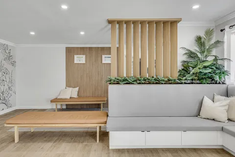 Room with a grey sofa, wooden bench, cushions and indoor plants