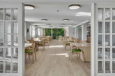Dining room with tables and green chairs viewed through glass doors