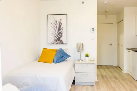 Bedroom with a single bed, bedside cabinet and pineapple artwork