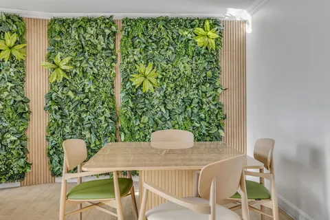Table and chairs beside a wall of green plants and wooden slats