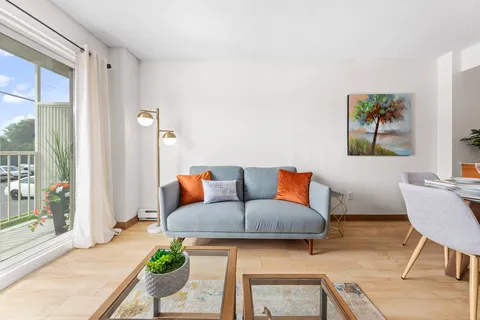 Apartment sitting area with a grey sofa, glass coffee tables and a balcony door