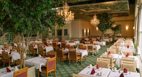 Dining room with set tables, wooden chairs and indoor trees