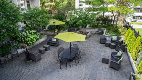 Paved garden patio with outdoor seating, umbrellas and planted borders