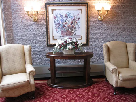 Two armchairs beside a table, flowers and a framed floral painting