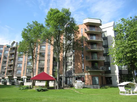 Residence with balconies beside a lawn, trees and a red-roofed gazebo