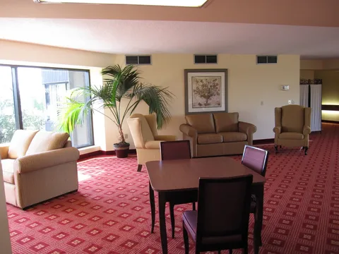 Sitting area with a sofa, armchairs, tables and a red patterned carpet