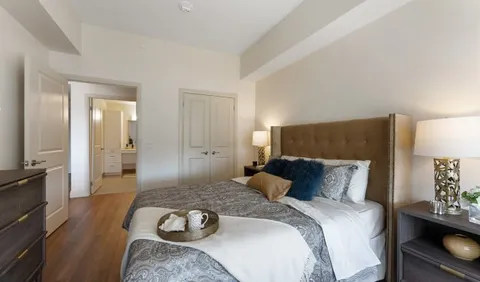 Bedroom with a bed, dresser, lamps and an adjoining hallway