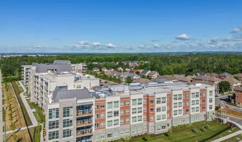Aerial view of a multistorey building with balconies beside landscaped grounds