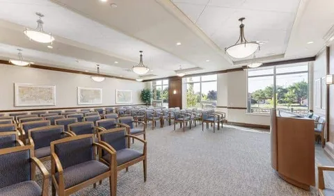 Room with rows of chairs, a lectern and large windows