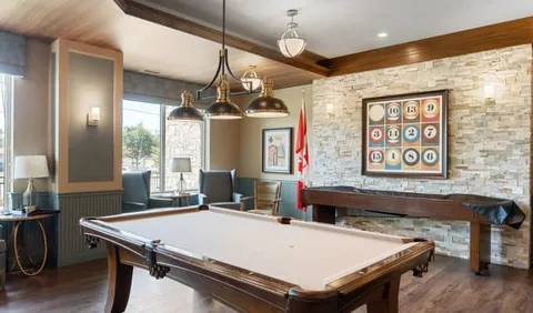Room with a pool table, framed numbered balls and armchairs