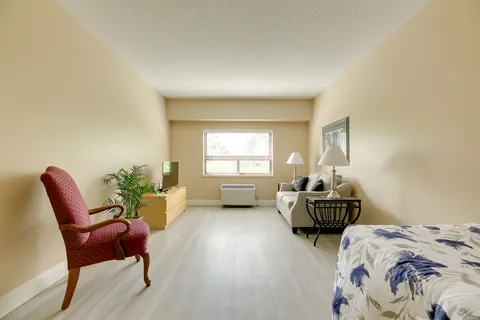 Room with a bed, sofa, red armchair and large window