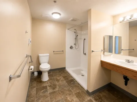 Bathroom with a vanity, toilet, shower and grab bars.