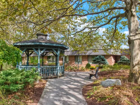 Garden path leading to a wooden gazebo among trees and shrubs
