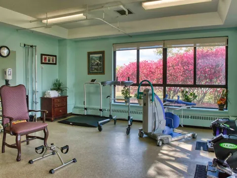 Room with exercise equipment, a chair and a large window