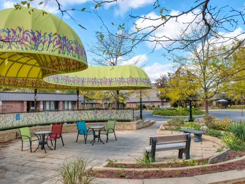 Patio with tables, colourful chairs, benches and large yellow canopies