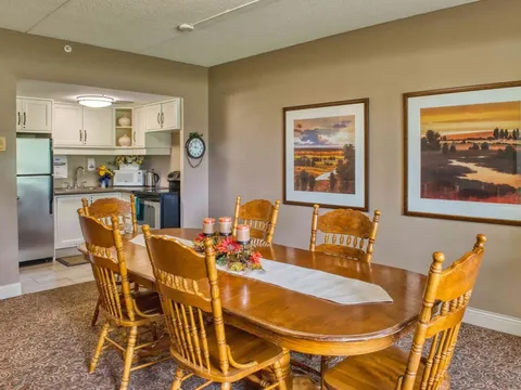 Room with a wooden dining table, chairs and a kitchen area