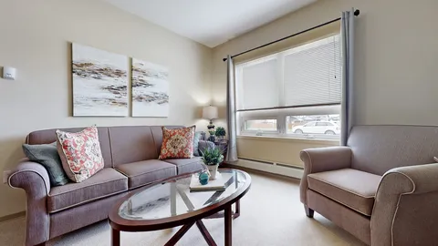 Room with a sofa, armchair, glass coffee table and large windows