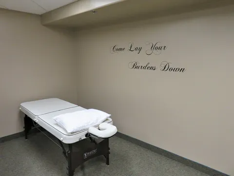 Treatment room with a padded massage table and beige walls