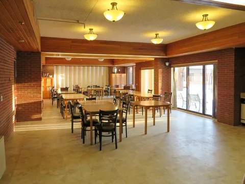 Room with wooden tables, black chairs, brick walls and glass patio doors