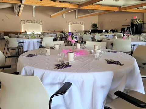 Dining room with round tables, white tablecloths, flower vases and a piano