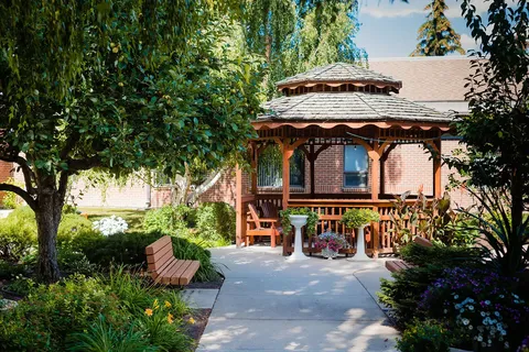 Garden path with benches, flower beds and a wooden gazebo