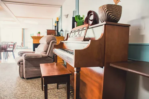Upright piano beside an armchair and wooden coffee table