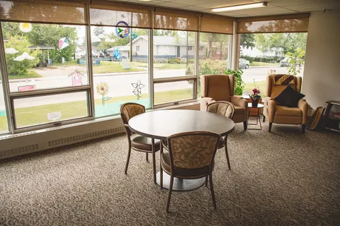 Windowed sitting area with armchairs, a round table and patterned carpet
