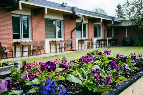 Single-storey brick building beside a patio and a raised flower bed