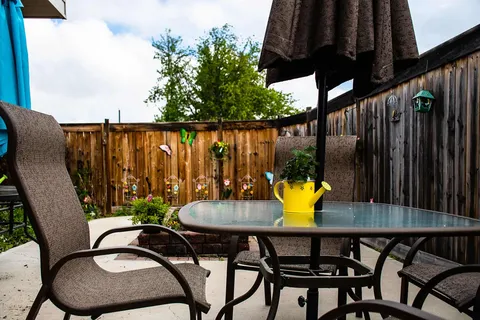 Patio table and chairs beside a wooden fence and flower baskets