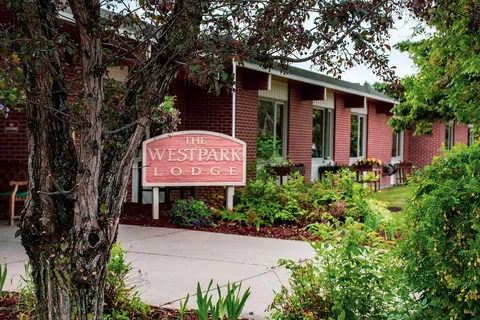 Brick building beside a sign, flower beds and a paved path