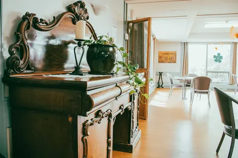 Wooden sideboard and mirror beside a doorway leading to tables and chairs