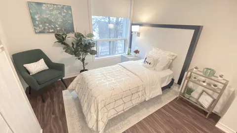 Bedroom with a single bed, green armchair, window and plant shelves