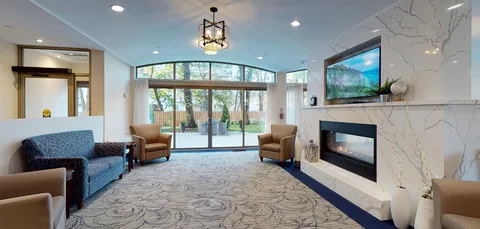Room with a blue sofa, tan armchairs, fireplace and glass doors to a patio