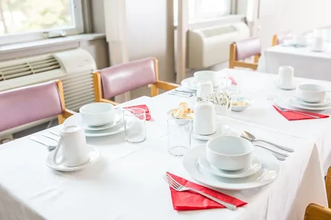 Dining room with tables, chairs and place settings.