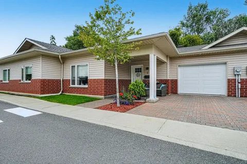 Single-storey brick and siding townhouse with a garage and front garden