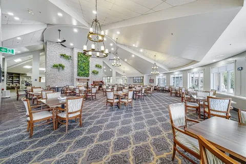 Dining room with wooden tables and chairs beneath chandeliers