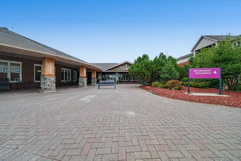 Covered entrance beside a paved forecourt and planting beds